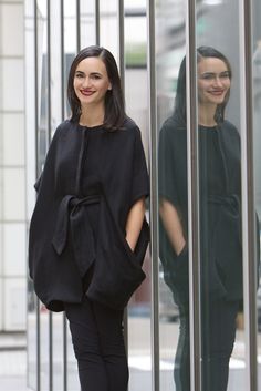 a woman standing in front of a glass wall with her hands on her hips and smiling