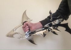 a person holding onto a metal shark with spikes on it's back and arms