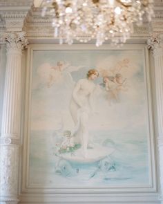 a painting on the wall in a room with chandelier