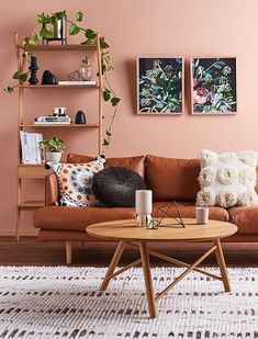 a living room with pink walls and furniture in the corner, including a brown leather couch