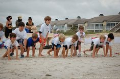 a group of young children standing on top of a sandy beach next to each other