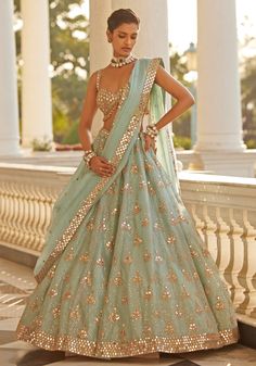 Elevate your style with our blue organza lehenga with mirror embroidery. This stunning ensemble features a luxurious organza lehenga adorned with intricate mirror and sequin embroidery in rose gold accents. Paired with a modern cut sleeveless blouse and a beautifully embellished dupatta featuring hand-cut mirrors, this set exudes elegance and sophistication. Perfect for a wedding reception, this lehenga set ensures the bride will make a memorable and dazzling impression on her special day. Composition : Lehenga - Organza, Dupatta - Organza, Blouse - Georgette Care: Dry Clean Only and Vacuum Storage This product can be customized for sleeves, length and colour Delivery : 6-8 weeks as the product is hand crafted. Check Size Guide or choose MySize for free customisation (All Sizes above XL ca Lehenga For Wedding Guest, Lengha Modern, Blue Indian Outfit, Modern Lehenga Designs, Blue Organza Lehenga, Modern Lehenga, Mirror Blouse, Culture Outfits, Intricate Mirror