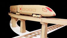 a toy train is sitting on top of a wooden rail road track that's attached to a cardboard box