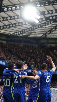 the soccer players are celebrating their team's goal in front of an arena full of people