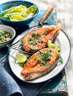 grilled salmon on a white plate with lemon wedges and garnishes