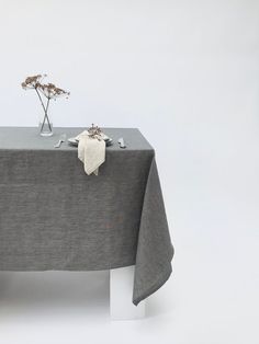 a table topped with a gray cloth and two small vases filled with flowers sitting on top of it