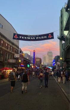 people are walking down the street in front of a sign that says fenway park