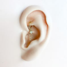 an ear is shown with a single diamond in it's middle, on a white surface