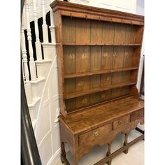 an old wooden bookcase sitting on top of a white floor next to a stair case