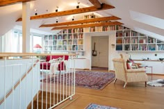 a living room filled with furniture and bookshelves next to a stair case in front of a window