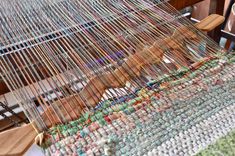 a close up of a weaving machine with yarn on the table and chairs in the background