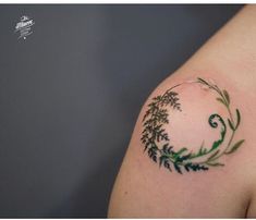 a tattoo on the arm of a woman with green leaves