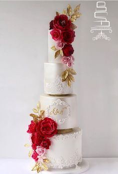 a three tiered wedding cake with red and pink flowers on the top, decorated with gold leaves