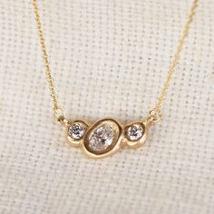 Organically sculpted 3 stone necklace, with one larger oval cut diamond and 2 small round diamonds on either side, bezel set in 14k yellow gold. 6x4mm Lab diamond Center / 3mm Lab diamond sides Total carat weight: .57ct Lab grown Diamonds Color: GH // Clarity VS2 Set on a 16"-18" adjustable 14KY chain Oval Rose Cut Diamonds Necklace In Fine Jewelry Style, Oval Rose Cut Diamond Necklace - Fine Jewelry, Fine Jewelry Oval Necklaces With Rose Cut Diamonds, Oval Rose Cut Diamond Necklace, 14k Gold Oval Diamond Necklace With Single Cut Diamonds, 14k Gold Oval Diamond Necklace For Anniversary, 14k Gold Oval Diamond Necklace With Gemstone, Oval 14k Gold Necklace With Single Cut Diamonds, Anniversary Oval Necklace With Rose Cut Diamonds