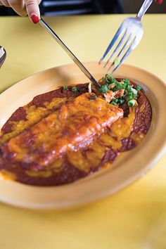 a person is cutting into some food on a plate