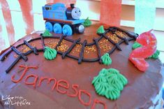 a birthday cake with a thomas the train on top and name written in frosting