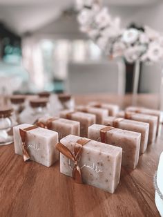 soaps with names on them sitting on a table next to wine glasses and flowers