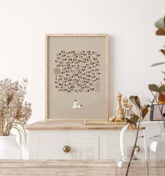 a table with some vases and plants on it next to a framed art piece