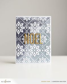 a card with the word noel written in gold on it and an ornate pattern background