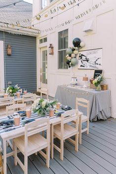 an outdoor dining area with tables, chairs and decorations on the outside deck at a house