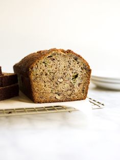 a loaf of zucchini bread sitting on top of a cooling rack next to some slices