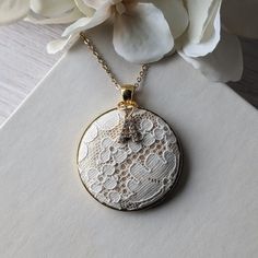 This vintage lace necklace is the perfect gift for those that love a timeless and elegant style. The white floral lace from the 1950s evokes a sense of delicate beauty, with a background of shiny gold satin that highlights the intricate lace design. It's set in a gold metallic metal alloy pendant, with a dainty gold stainless steel chain that measures 22 inches in total length. Letter charm: The finishing touch is the capital letter initial charm that adorns the top of the pendant. This charm offers the perfect way to make this necklace a thoughtful and personalized gift. Gift box: The necklace will be packaged in a stylish, branded gift box, ready to be presented with love and care.  Gift notes:  Write a personalized note to your loved one at checkout, and it will be printed on decorative Delicate Lace Wedding Jewelry, White Lace Necklace For Wedding, Vintage Beige Necklace For Gift, Delicate White Lace Jewelry, Vintage Beige Necklace For Gifts, Vintage Beige Necklace Gift, White Vintage Necklace With Vintage Charm, White Vintage Necklace With Charm, Elegant Vintage Charm Necklace For Anniversary