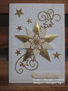 a white card with gold stars and swirls in the middle, on top of a wooden table