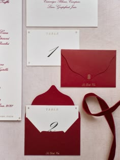 the wedding stationery is laid out on top of each other, including red and white envelopes