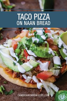 taco pizza on naan bread topped with avocado, tomatoes and cilantro