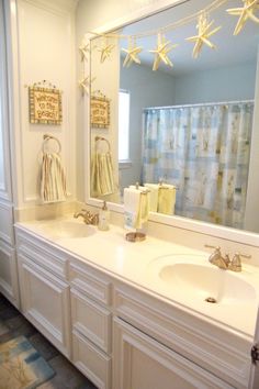 a bathroom with two sinks and a large mirror in it's center, decorated with starfish decorations