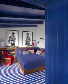 a bedroom with blue walls and flooring has two pictures on the wall above the bed