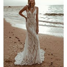 a woman standing on top of a sandy beach next to the ocean wearing a dress