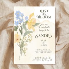 a card with flowers on it is sitting on a bed sheet in front of a blanket