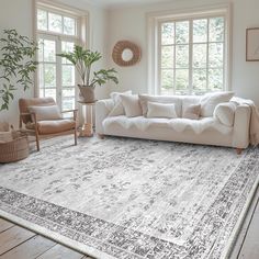 a living room filled with lots of furniture and large rug on the floor in front of two windows