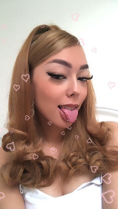 a woman sticking her tongue out with hearts drawn all over her face in front of her