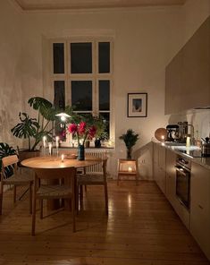 a dining room table with candles on it in front of an open window and potted plants