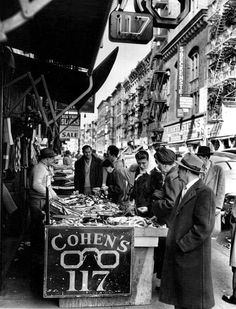 Orchard Street sidewalk vendors (belts, ties) & sign for Cohen’s Optical, Orchard Street in 1950.  Cohen’s Optical & their competitor on the other side of Delancey St., Sol Moscot, are two of the few remaining longtime Lower East Side businesses. In 1927, Jack Cohen started selling ready-made glasses from a pushcart on Orchard St. & later opened a retail store on Orchard & Delancey Streets, which is still there. According to their website, they were the first optical retailer in NYC to sell “fas Street Sidewalk, Lower East Side Nyc, East Side New York, Old Nyc, Old New York, Nyc Aesthetic, Side Business, Lower East Side, East Side