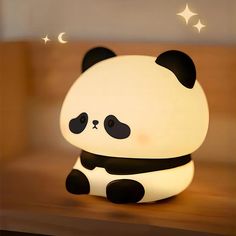 a panda bear night light sitting on top of a wooden table next to a window