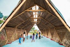 several people are standing in the middle of a building with thatched roof and walls