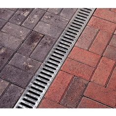 two metal grates sitting on top of a red brick sidewalk next to each other