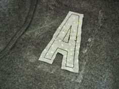 the letter a is made out of felt and thread on top of a piece of fabric