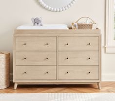 a baby crib with a mirror above it and a teddy bear on the dresser