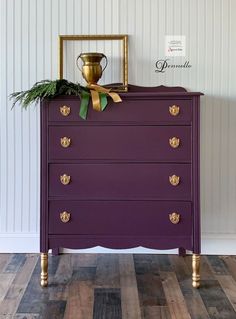 a purple chest of drawers with gold handles