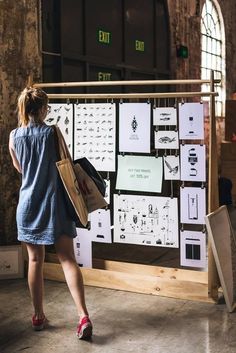 a woman standing in front of a display with lots of drawings on it and shopping bags