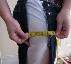 a person is measuring their waist with a tape around his waist and there are vegetables in the background