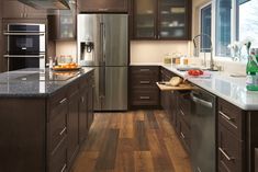 a modern kitchen with stainless steel appliances and wood flooring is pictured in this image