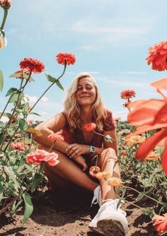 a woman sitting on the ground surrounded by flowers