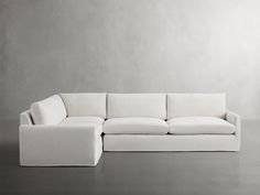 a white couch sitting on top of a floor next to a gray wall and wooden floors