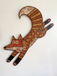 a wooden cut out of a fox on a white wall