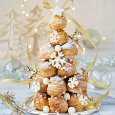 a christmas tree made out of doughnuts on a plate with gold ribbon and snowflakes